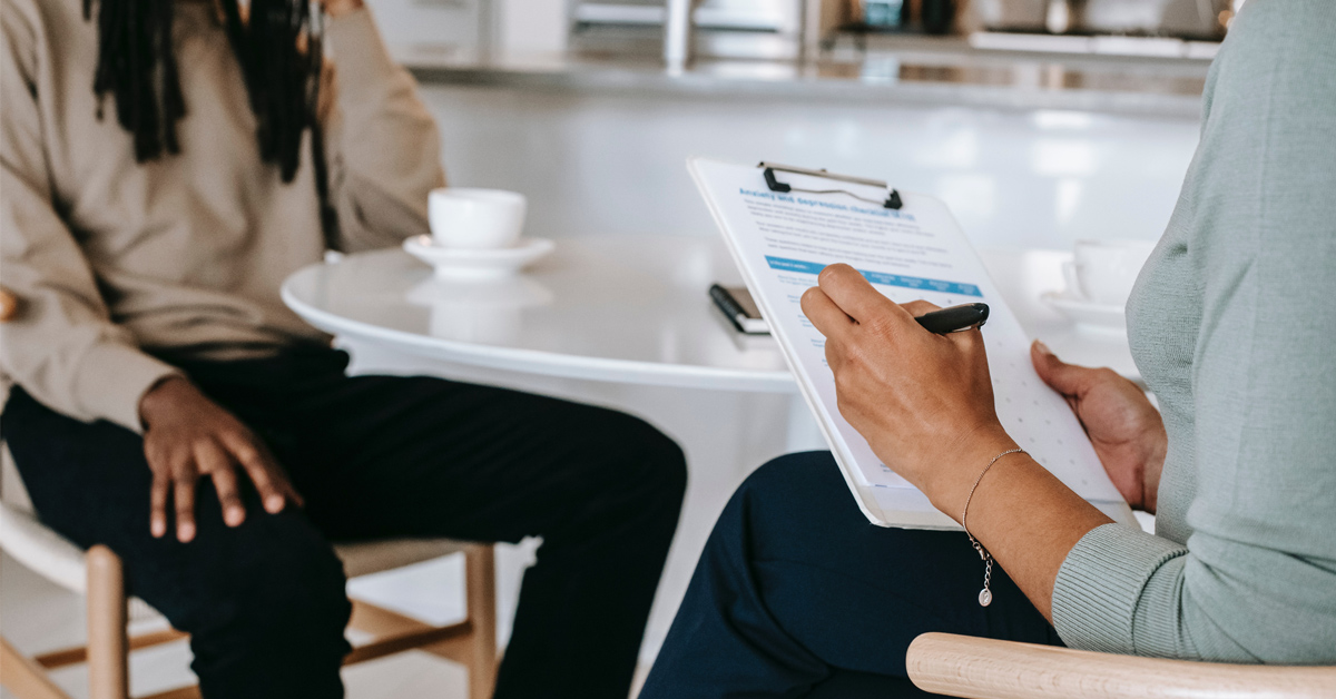 Two people sitting across from each other at a table filling out a questionnaire